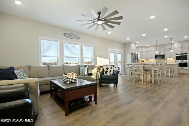 living room with light hardwood / wood-style floors, french doors, and ceiling fan