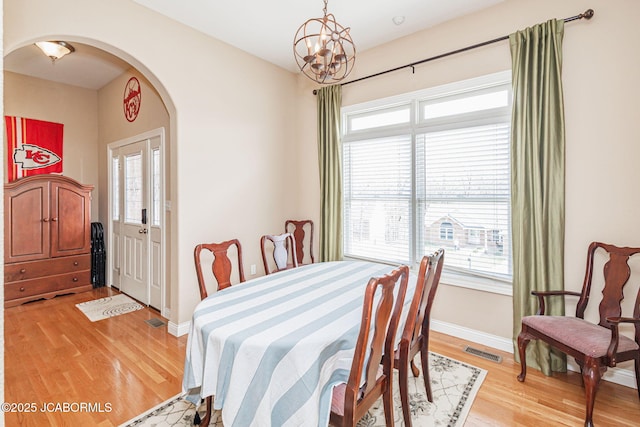 2414 Camzie Dr, Jefferson City, MO 65101 - dining space featuring baseboards, a chandelier, light wood-style floors, visible vents, and arched walkways