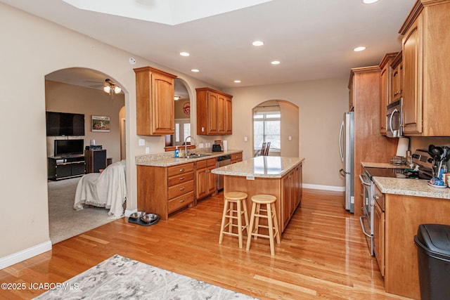 2414 Camzie Dr, Jefferson City, MO 65101 - kitchen featuring a center island, a kitchen bar, appliances with stainless steel finishes, arched walkways, and a sink