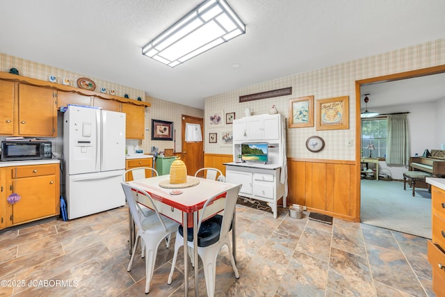 409 Lorene St, California, MO 65018 - dining space with wallpapered walls, a wainscoted wall, light stone finish floors, ceiling fan, and a textured ceiling