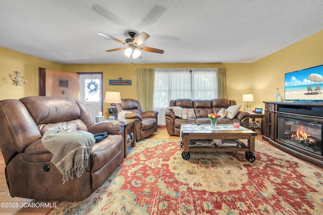 409 Lorene St, California, MO 65018 - living room featuring a ceiling fan, a textured ceiling, a glass covered fireplace, and wood finished floors