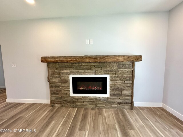 details with hardwood / wood-style floors and a stone fireplace