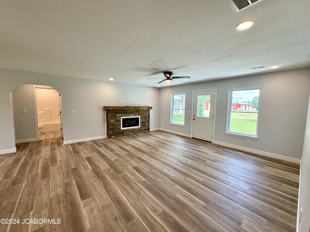 unfurnished living room featuring a fireplace, a textured ceiling, hardwood / wood-style flooring, and ceiling fan