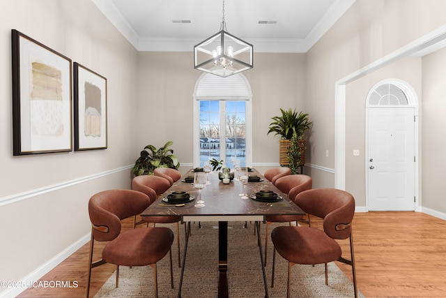 dining area featuring light wood-style floors, visible vents, an inviting chandelier, and ornamental molding