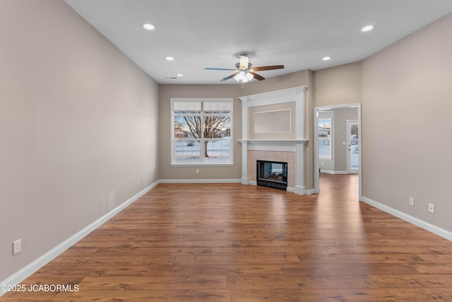 unfurnished living room featuring wood finished floors, baseboards, and a ceiling fan