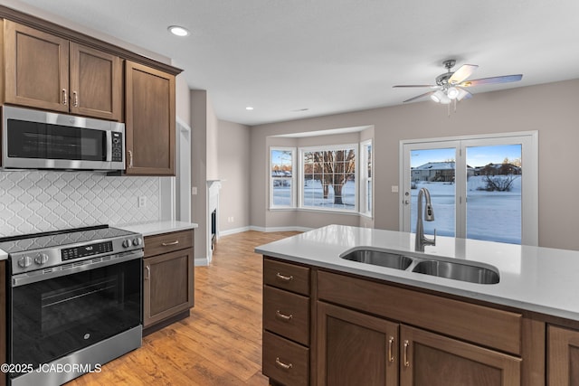 kitchen featuring a sink, ceiling fan, appliances with stainless steel finishes, light countertops, and backsplash