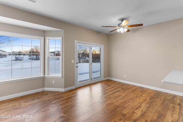 unfurnished room with wood-type flooring, baseboards, and a ceiling fan