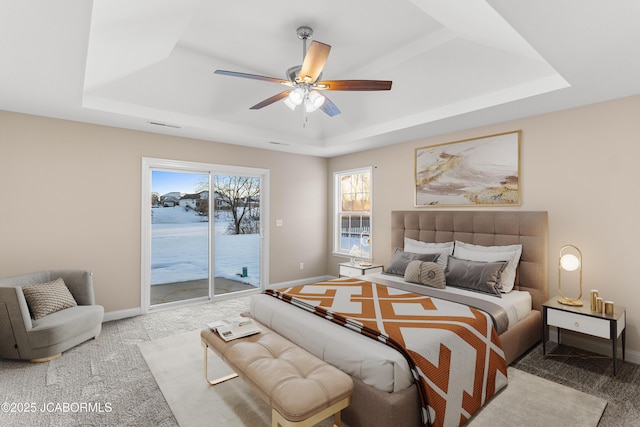 carpeted bedroom featuring visible vents, baseboards, a raised ceiling, a ceiling fan, and access to outside