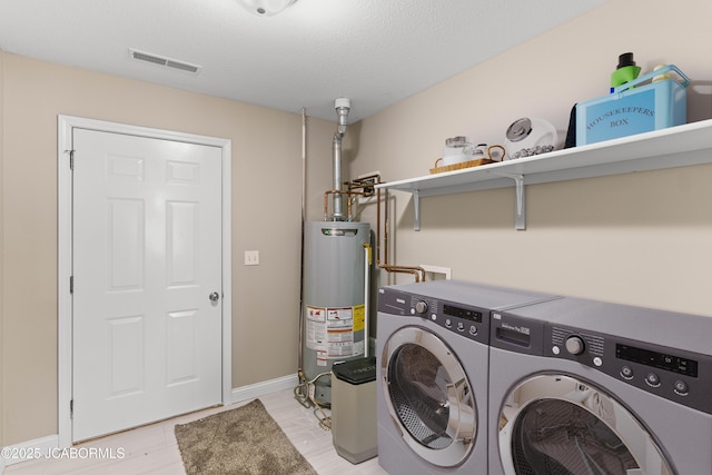 clothes washing area with water heater, baseboards, visible vents, independent washer and dryer, and laundry area
