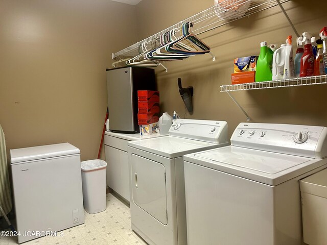 clothes washing area featuring laundry area, washing machine and dryer, and light floors