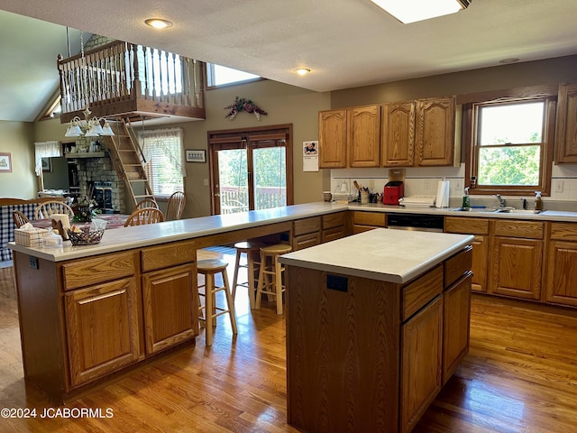 kitchen with a peninsula, a sink, open floor plan, light countertops, and a kitchen bar