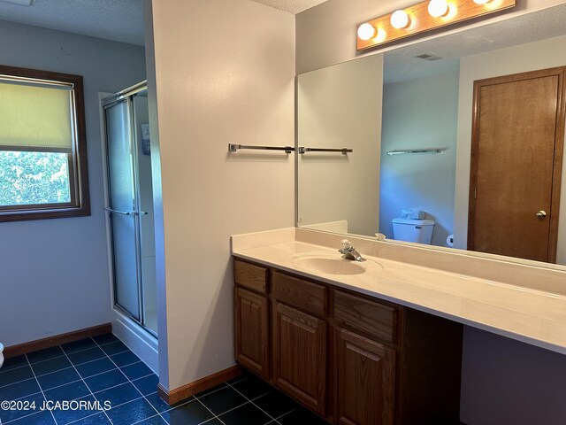 bathroom with tile patterned flooring, toilet, a shower stall, and vanity