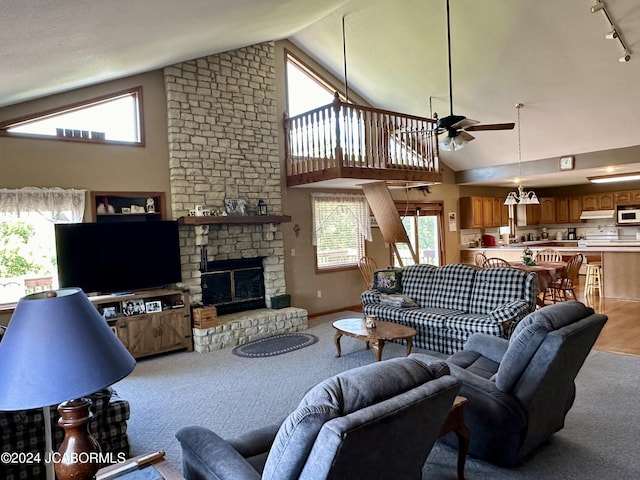 living area with ceiling fan, high vaulted ceiling, a fireplace, baseboards, and rail lighting