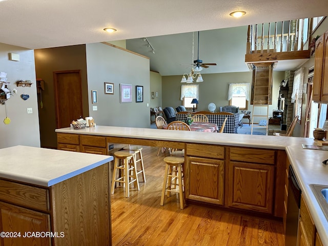 kitchen with a kitchen breakfast bar, open floor plan, light countertops, light wood-type flooring, and brown cabinets