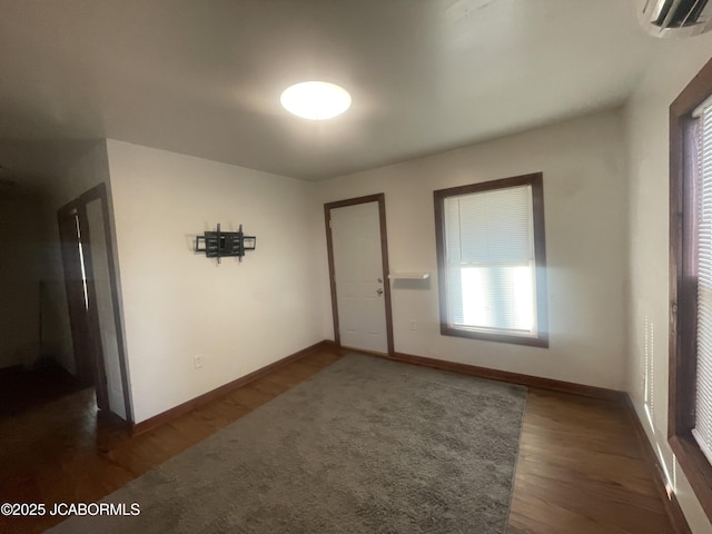 empty room with dark hardwood / wood-style flooring and a wall mounted AC