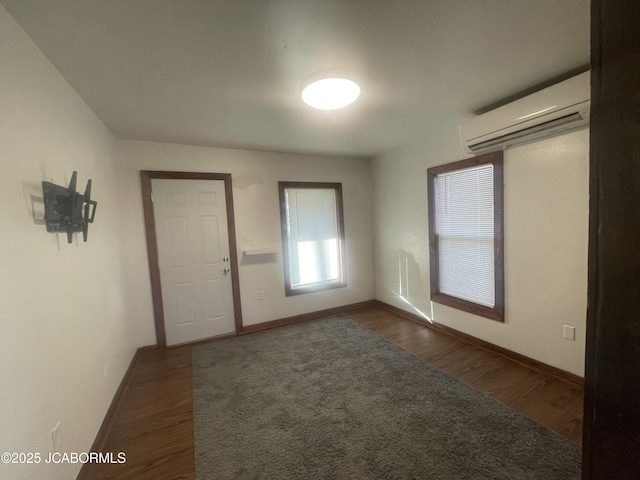 empty room featuring dark hardwood / wood-style flooring and a wall unit AC