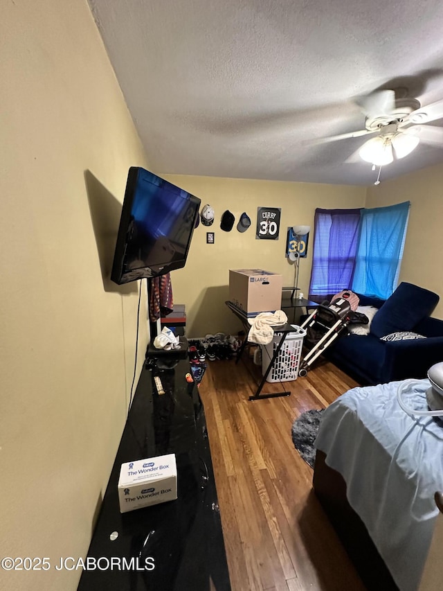 bedroom featuring ceiling fan, hardwood / wood-style flooring, and a textured ceiling