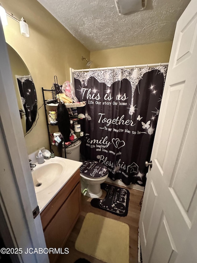 bathroom featuring vanity, hardwood / wood-style floors, a textured ceiling, and toilet