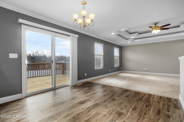 empty room with hardwood / wood-style floors, a tray ceiling, ceiling fan with notable chandelier, and ornamental molding