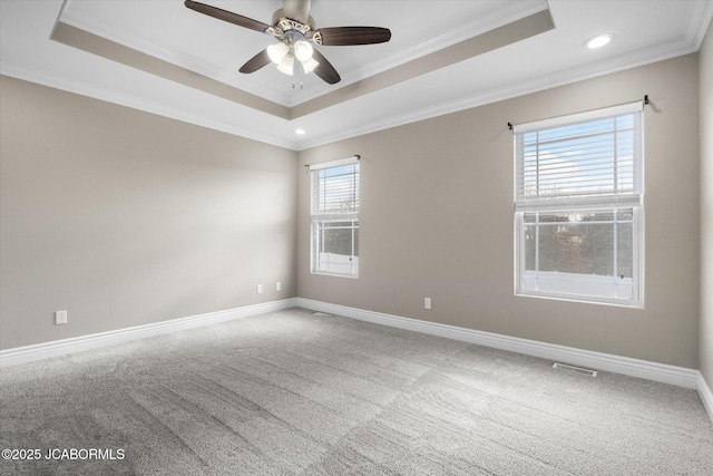 carpeted spare room with a tray ceiling, ornamental molding, and ceiling fan