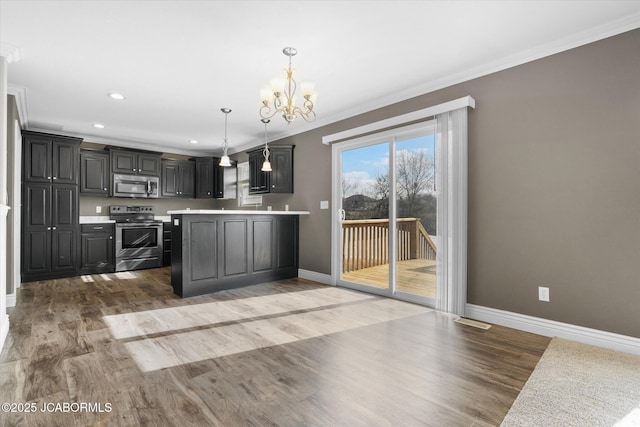 kitchen featuring decorative light fixtures, a chandelier, ornamental molding, stainless steel appliances, and hardwood / wood-style floors