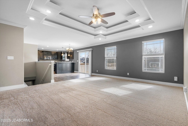 unfurnished living room featuring crown molding, ceiling fan with notable chandelier, light colored carpet, and a tray ceiling