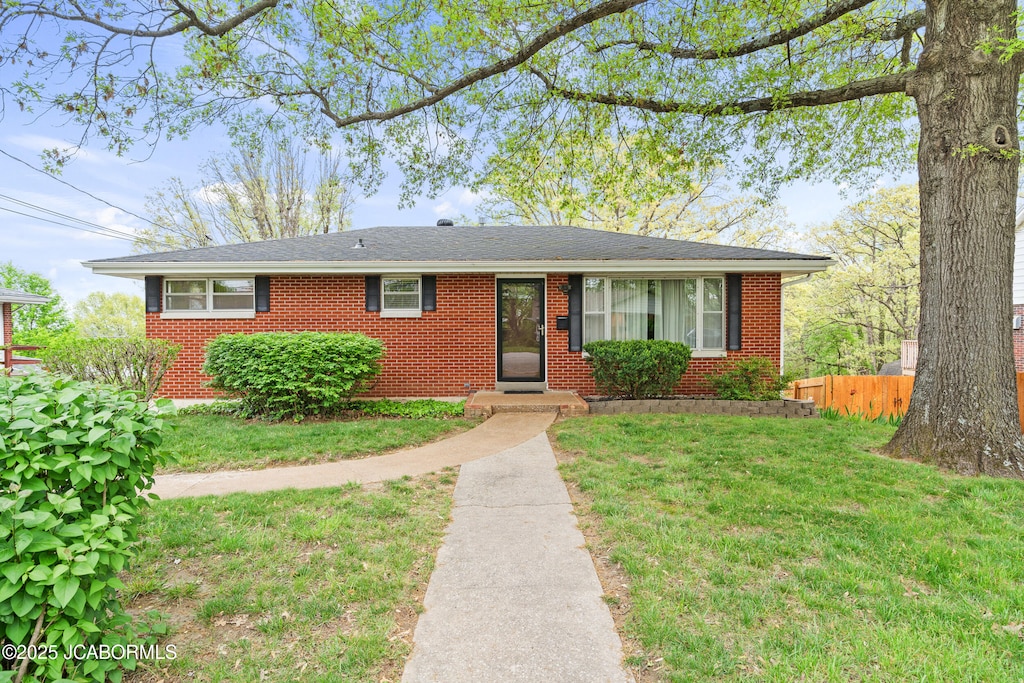 1213 Edgewood Dr, Jefferson City, MO 65109 - view of front facade featuring fence, a shingled roof, a front lawn, and brick siding