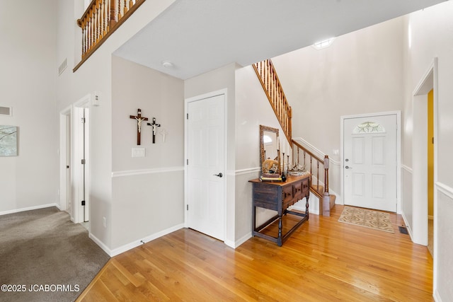 entryway featuring a towering ceiling and wood-type flooring