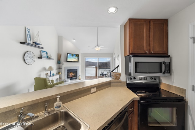 kitchen featuring lofted ceiling, stainless steel microwave, electric range, a sink, and a warm lit fireplace