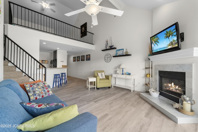 living area with high vaulted ceiling, a ceiling fan, baseboards, and wood finished floors