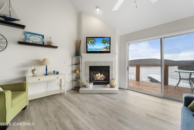 living area featuring high vaulted ceiling, ceiling fan, a premium fireplace, and wood finished floors