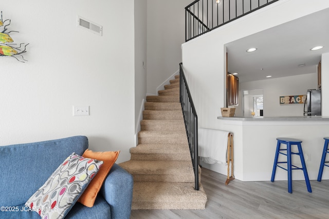 stairs with visible vents, wood finished floors, and recessed lighting