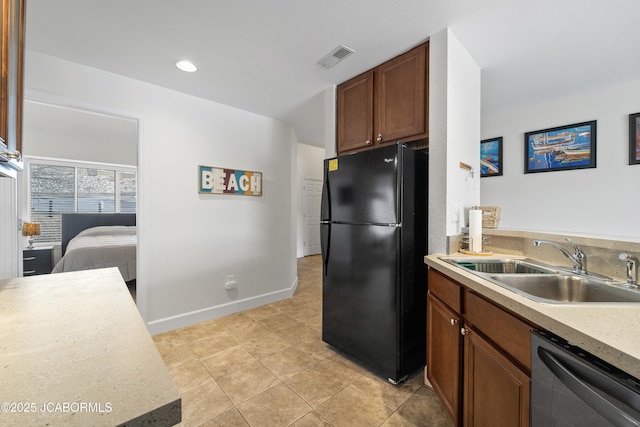 kitchen featuring visible vents, dishwasher, freestanding refrigerator, light countertops, and a sink