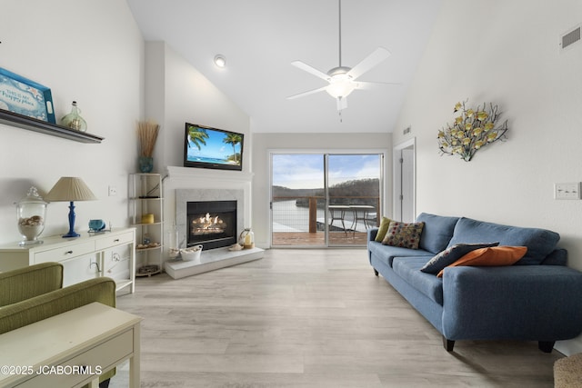 living room featuring light wood-style floors, visible vents, a premium fireplace, and high vaulted ceiling