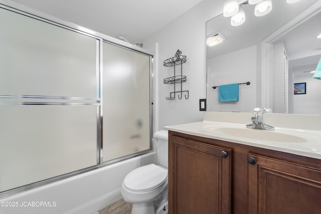 bathroom featuring enclosed tub / shower combo, vanity, and toilet