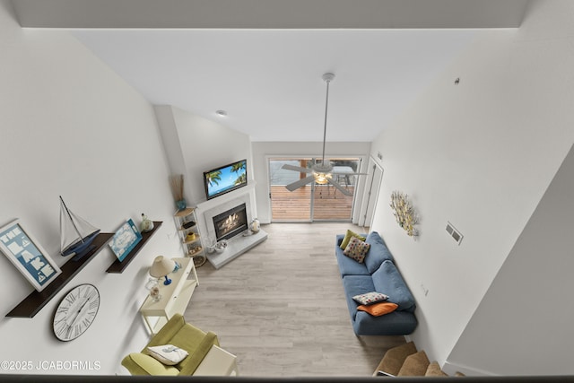 living room with ceiling fan, wood finished floors, and a glass covered fireplace