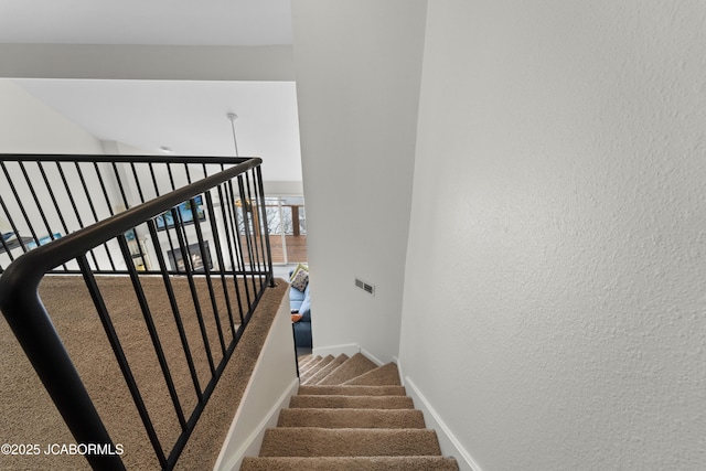 staircase featuring carpet floors and baseboards