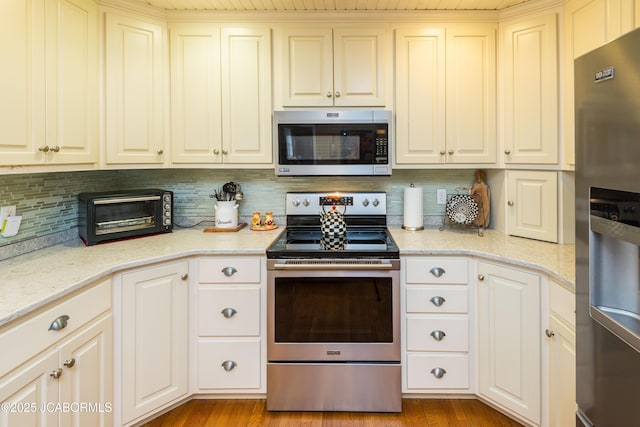 kitchen featuring appliances with stainless steel finishes, backsplash, a toaster, and light wood-style flooring