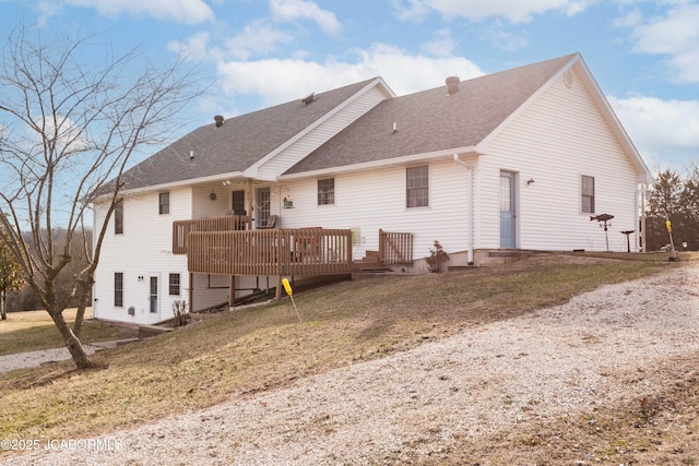 rear view of property with a deck, a lawn, and roof with shingles