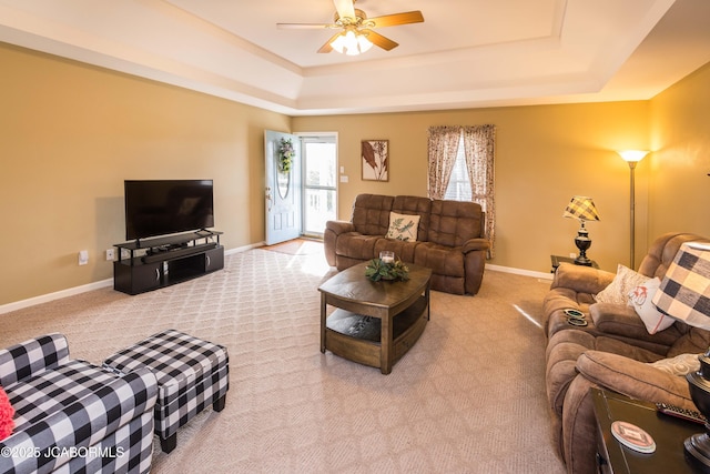 living area featuring light carpet, a raised ceiling, and baseboards