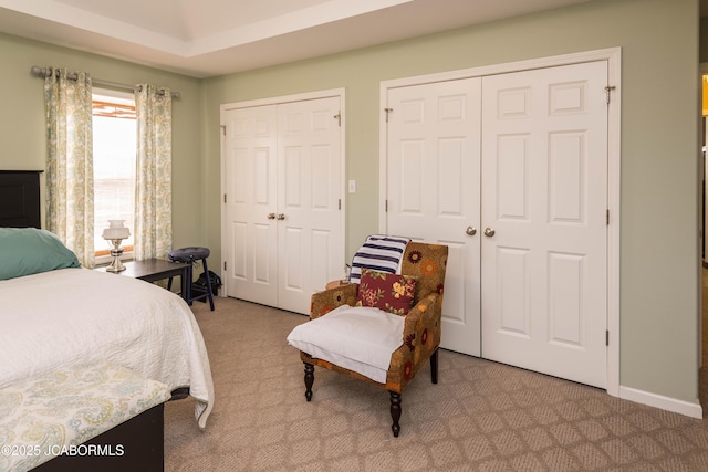 bedroom with carpet, baseboards, and two closets