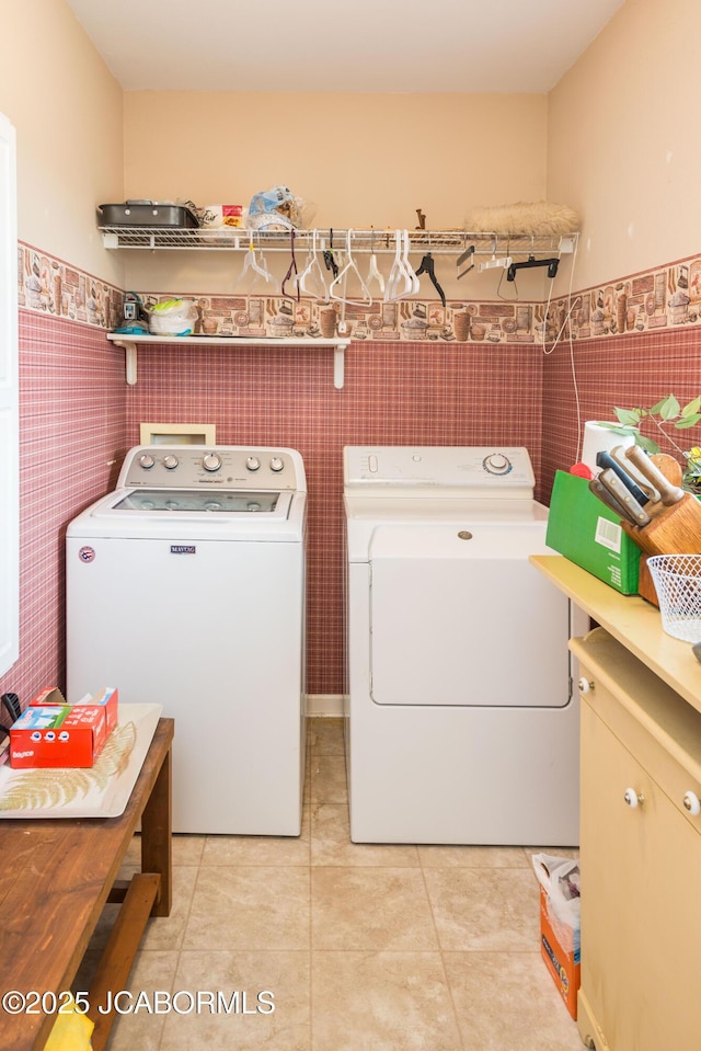 washroom featuring light tile patterned floors, tile walls, washer and dryer, and wainscoting