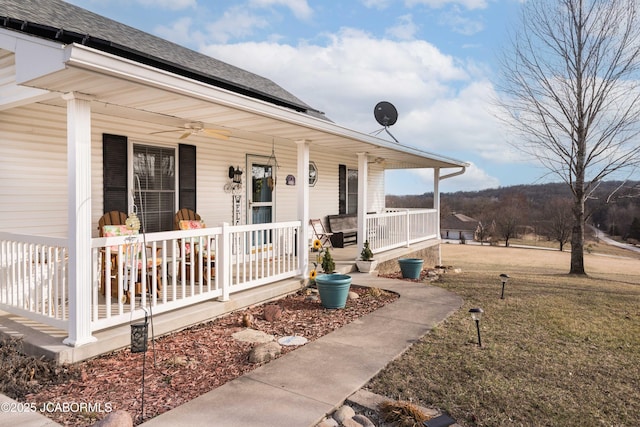 view of front of home featuring a shingled roof, covered porch, a front yard, roof mounted solar panels, and ceiling fan