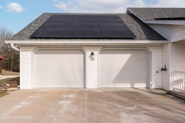 garage with driveway and solar panels