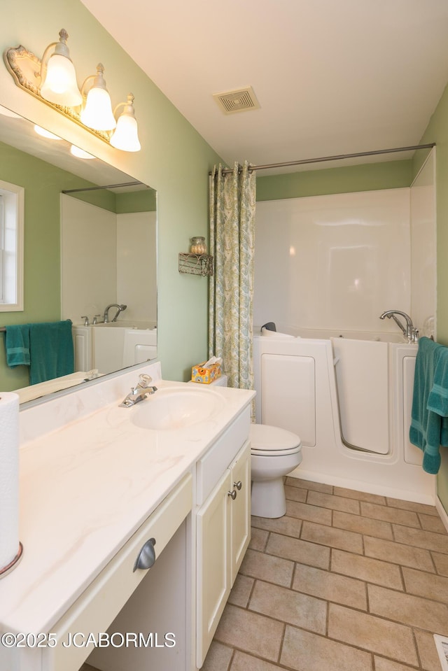 bathroom featuring toilet, visible vents, a bathtub, and vanity