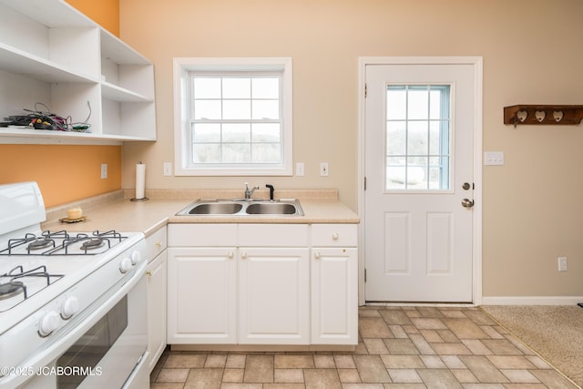 kitchen with plenty of natural light, white gas range oven, open shelves, and a sink