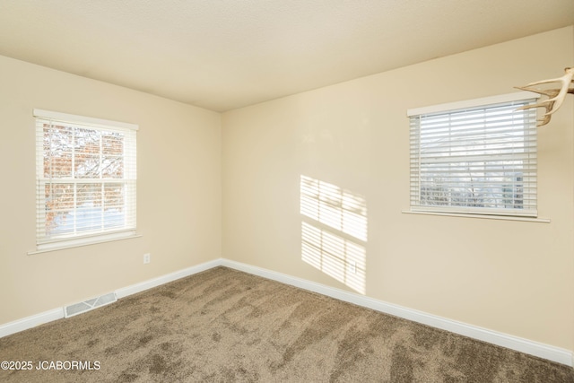 carpeted empty room with visible vents and baseboards