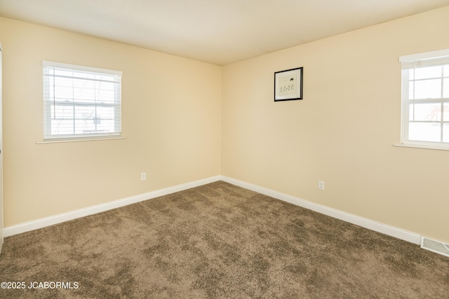 unfurnished room featuring carpet, visible vents, and baseboards