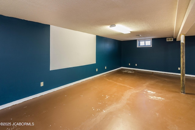 basement featuring a textured ceiling, visible vents, and baseboards