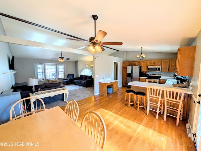 dining room featuring vaulted ceiling, ceiling fan with notable chandelier, and light hardwood / wood-style flooring